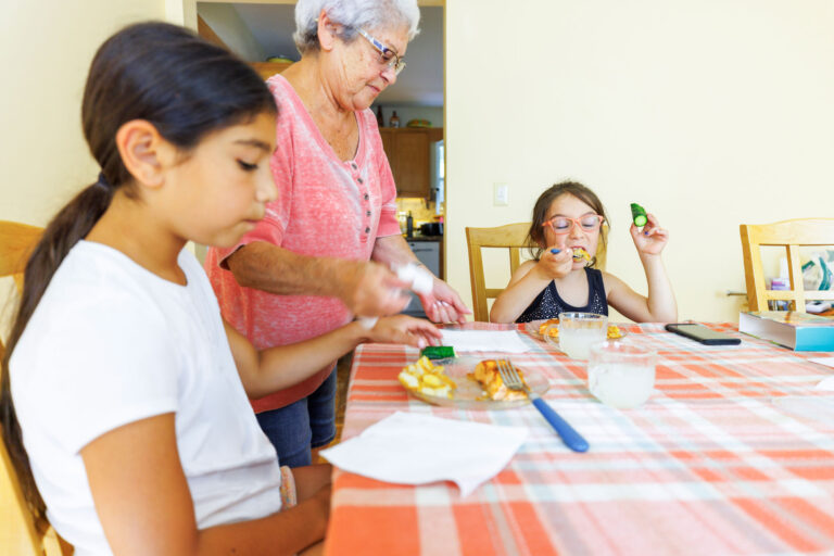photo - Grandmother Serving Food to her Granddaughters at Dining Room Table