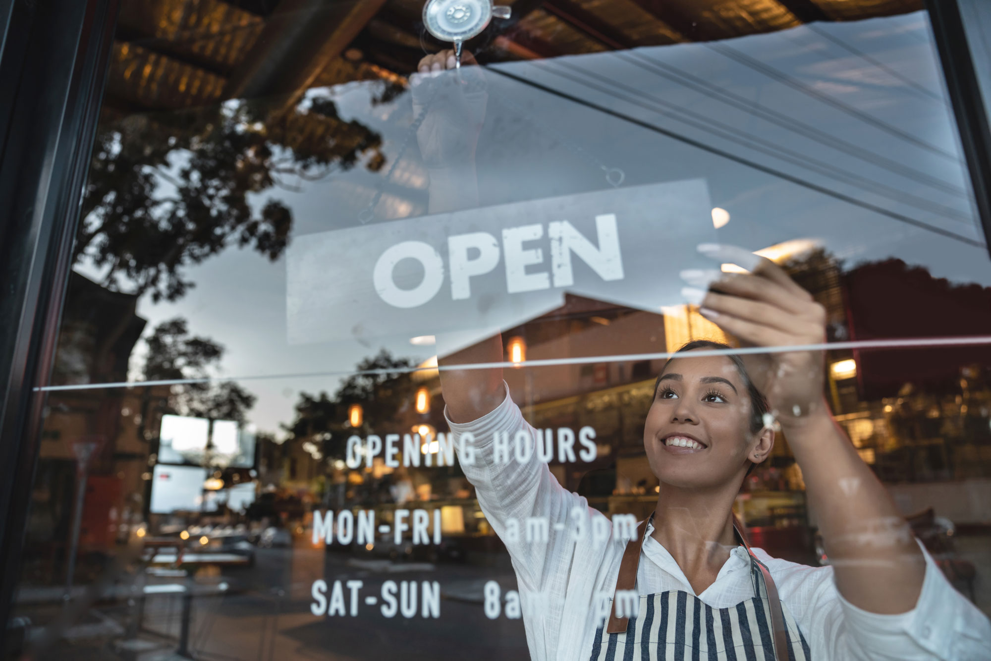 Happy business owner hanging an open sign at a restaurant