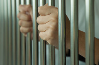 photo - Inmate's Hands on Cell Bars