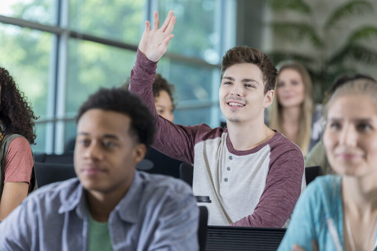 photo - Male College Student Raises Hand in Class