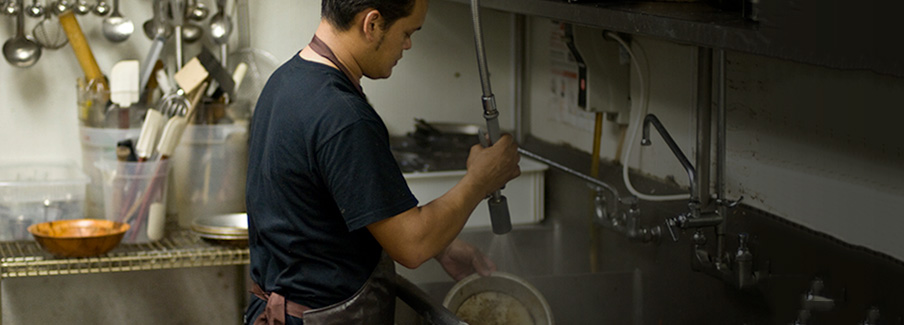 Photo of a man working at a restaurant washing dishes Working
