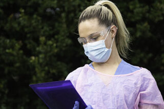 photo - Nurse Wearing Protective Workwear and Holding Paperwork
