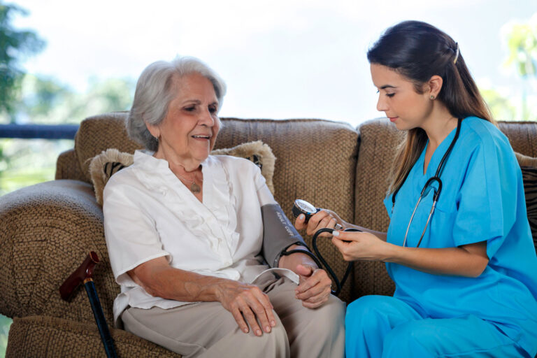 photo - Nursing Home Assistant Taking Blood Pressure of Senior Woman
