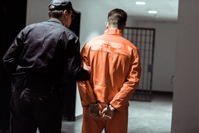photo - Prison Officer Leading Prisoner in Handcuffs