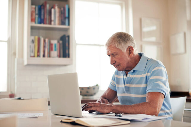 photo - Senior Man Using Laptop at Home