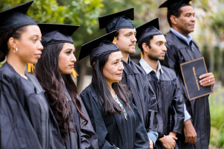 photo - Serious College Graduates Standing in Line at Graduation