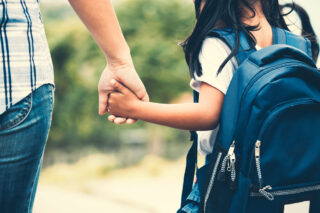 photo - Student Wearing Backpack and Holding Mother's Hand While Walking Together