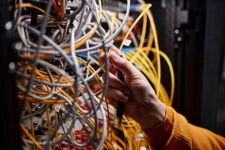 photo - Technician Connecting Cables and Wires in Server Cabinet