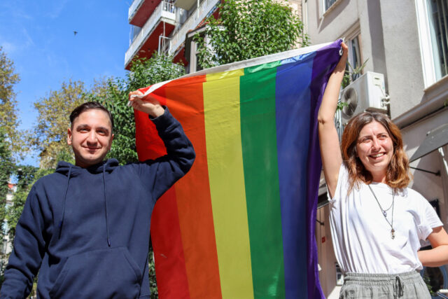 photo - Two People Carrying a Rainbow Flag Down Street