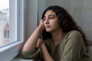photo - Unhappy Young Woman Looking Out Window