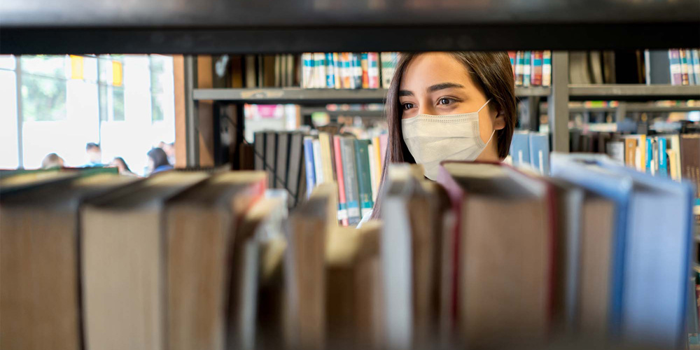 photo - View of Masked Young Woman in Library