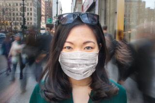 photo - Woman in Crowd Wearing Surgical Mask