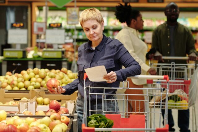 photo - Woman Looking at Shopping List in Grocery Store