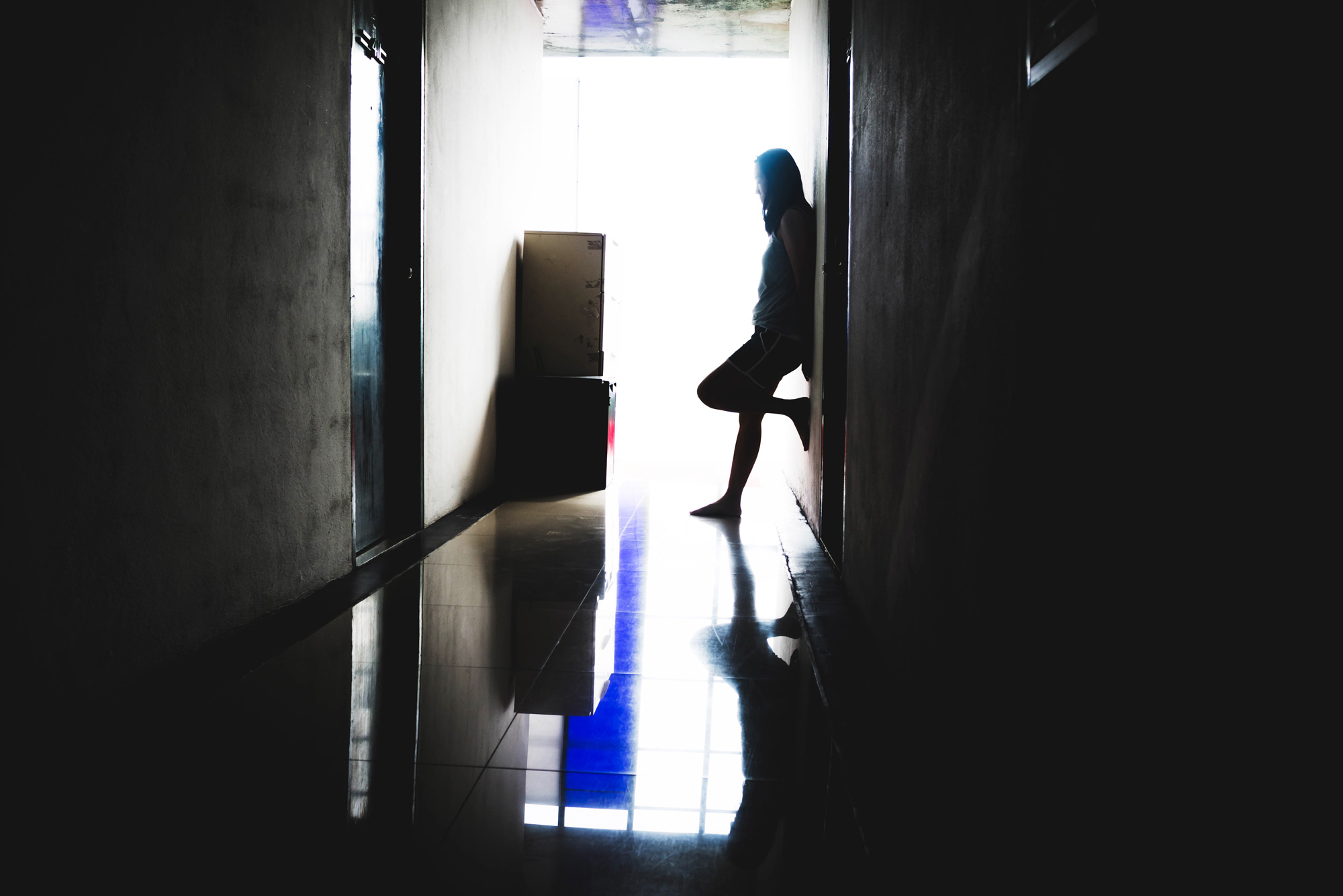 photo - Woman Standing at the End of a Dark Corridor