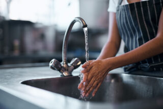 photo - Woman Washing Hands in Kitchen Sink