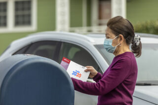 photo - Woman Wearing Mask at Mailbox, Mailing in Ballot