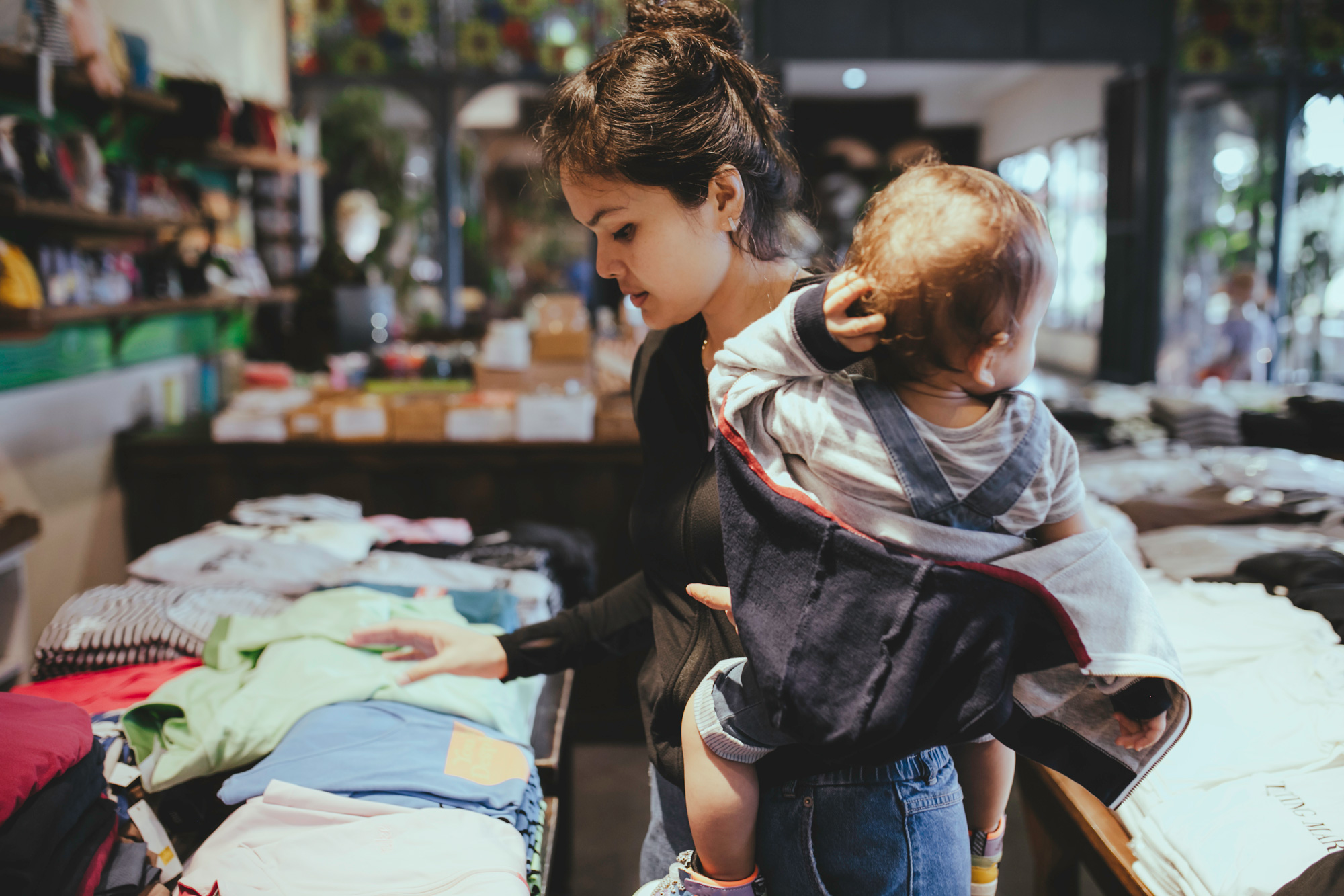 photo - Woman Carrying Her Baby and Clothes Shopping