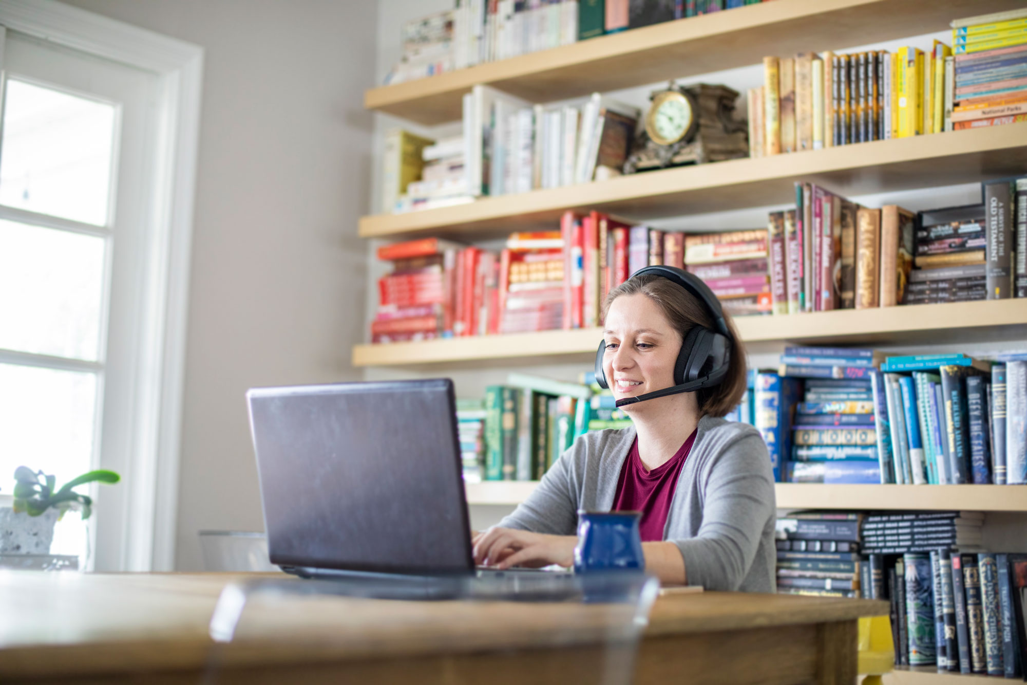 photo - Woman Working from Home Using Laptop and Wearing Headphones