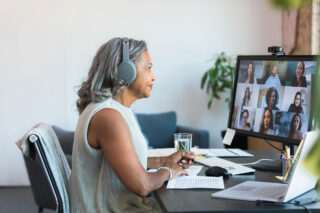 photo - Woman Working from Home Wearing Headphones and on a Zoom Meeting