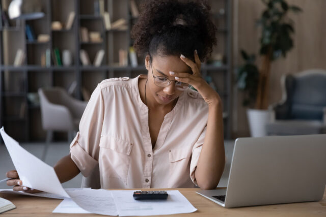 photo - Worried Woman Looking at Financial Paperwork