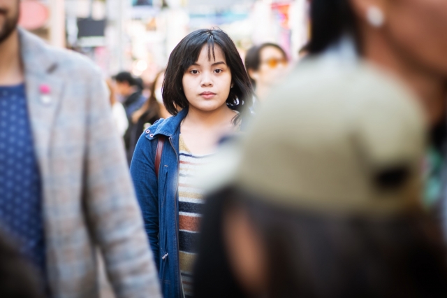 photo - Young Woman Standing in the Middle of a Crowded Street
